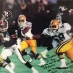 Football game action with player in orange and white uniform evading defenders in red and white uniforms, autographed photo