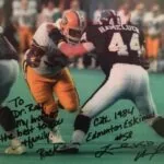 Vintage football game action photo with two players, one in orange jersey and one in dark jersey numbered 45, signed by players
